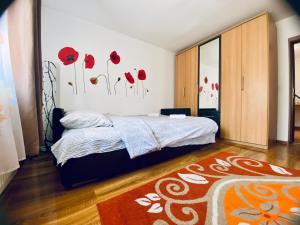 a bedroom with a bed with red flowers on the wall at Closca Apartment 1 Max in Floreşti