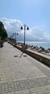 a sidewalk next to the ocean with street lights at Kelly's Rooms in Polisi i Vogël