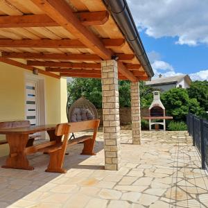 a wooden pergola with a bench on a patio at Holiday House Rose in Karlobag
