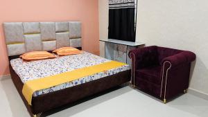 un dormitorio con una cama y una silla en The Aurelia Inn, en Sibsāgar