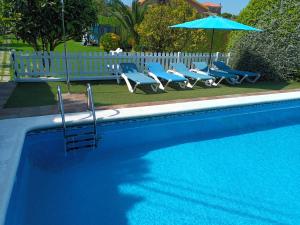 a swimming pool with chairs and a blue umbrella at Apartamento Pueblo De Mogro in Mogro