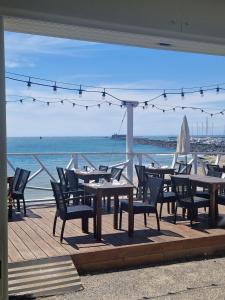 a patio with tables and chairs and the ocean at Studio les pieds dans l'eau in Cap d'Agde