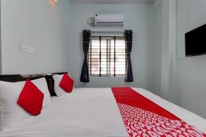 a bedroom with a bed with red pillows and a window at Super Hotel O PM Hotels in Bengaluru