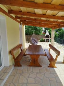 a wooden table and two benches on a patio at Holiday House Rose in Karlobag