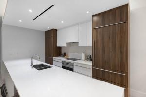 a kitchen with white counters and wooden cabinets at Modern Condo at One Cable Beach with Balcony in Nassau