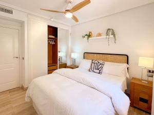 1 dormitorio con 1 cama con sábanas blancas y ventilador de techo en Apartamento en Resort de lujo Isla del Fraile, en Águilas