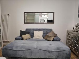 a blue couch in a living room with a mirror at La Petite Blanche in Cologne