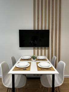 a table with white chairs and a television on a wall at LARIMAR Lungomare Vlore in Vlorë