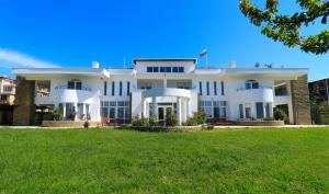 a large white house with a green lawn at Ravda Residence in Ravda