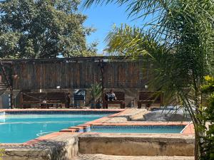 a man sitting on a bench next to a swimming pool at Gem Villa Inn in Lesoma