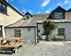 a wooden picnic table in front of a house at Cottage On The Brook in Braithwaite