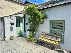 a wooden bench sitting outside of a white house at Cottage On The Brook in Braithwaite