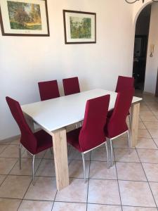 a white table with red chairs in a room at Casa dei Nonni in San Damiano dʼAsti