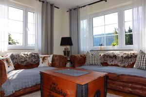 a living room with brown leather couches and windows at Ferienhaus Feldberg in Mittelfalkau