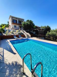 a swimming pool with two chairs next to a house at Bellavista Panorama Darmarochori in Darmarochori
