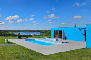 a blue house with a swimming pool and a body of water at Domki Rekreacyjne "Błękitne Wzgórze" in Żałe