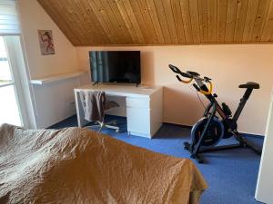 una camera da letto con un tapis roulant e una scrivania con una televisione di Ferienhaus Leuchtturmblick Hafendorf Rheinsberg a Rheinsberg