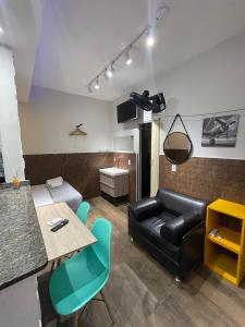 un salon avec un canapé en cuir noir et une table dans l'établissement Tiny house AR, Wi-Fi, TV cozinha, proximo a Unig, à Nova Iguaçu