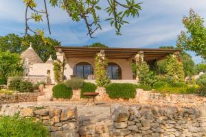 a home with a stone wall and a stone house at CANTALANOTTE Luxury Trulli Resort in Cisternino