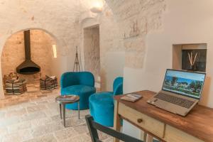 a room with a desk with a laptop and blue chairs at CANTALANOTTE Luxury Trulli Resort in Cisternino