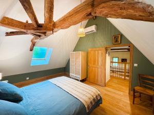 a bedroom with a blue bed in a attic at Petite maison rurale in Anlhiac