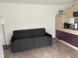 a black couch in a room with a kitchen at Neuer Bungalow in Motzen bei Berlin nur 300 m vom See und Strandbad entfernt in Mittenwalde