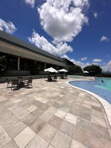 einen Pool mit Tischen und Sonnenschirmen neben einem Gebäude in der Unterkunft Bangalô monte castelo in Sairé