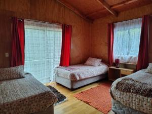 a bedroom with two beds and a window with red curtains at La Casona De Junia in Puerto Rico