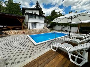 a swimming pool with lounge chairs and an umbrella at Villa IMAN in Sarajevo