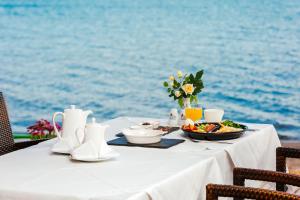 Cunda Hotel في أيفاليك: طاولة بيضاء مع طبق من الطعام على الماء