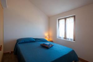 Un dormitorio con una cama con una manta azul y una ventana. en Elicriso, en Costa Paradiso