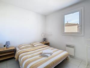 a white bedroom with a bed and a window at Maison "Havre de Paix" dans résidence avec piscine in Vias