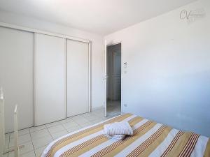 a white bedroom with a bed and a mirror at Maison "Havre de Paix" dans résidence avec piscine in Vias