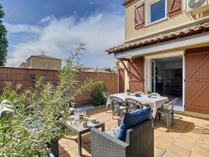 a patio with a table and chairs and a fence at Maison "Havre de Paix" dans résidence avec piscine in Vias