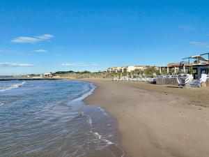 a beach with chairs and the ocean on a sunny day at Maison "Havre de Paix" dans résidence avec piscine in Vias