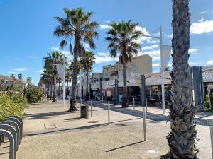a row of palm trees on a city street at Maison "Havre de Paix" dans résidence avec piscine in Vias
