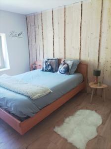 a bedroom with a bed with blue sheets and a rug at Le refuge de la source in Bussang
