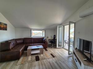 a living room with a brown leather couch and a television at Cozy, Fully Equipped, Free parking&Wifi, Quiet, 2BD in Podgorica