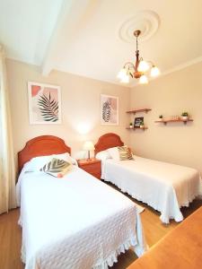 two beds in a room with white sheets at Lannion in Viveiro +10 photos