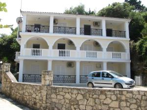 a white building with a car parked in front of it at Anemone Blue Seaside Apartments in Zakynthos Town