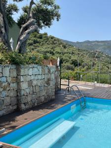 a blue swimming pool with a stone wall and a stone wall at inKanto Room in Cefalù