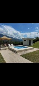 een zwembad met stoelen en een parasol naast een huis bij FINCA LA MIEL en Barbosa Antioquia in Barbosa