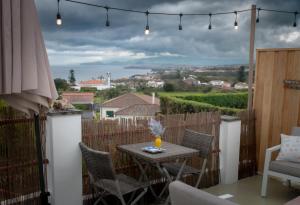 a patio with a table and chairs on a balcony at Casa da Fonte de Cima in Capelas