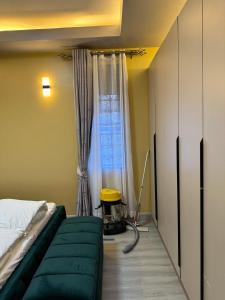 a bedroom with a green couch and a window at Mirembe housing in Nalakonge