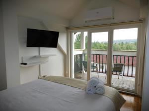 a bedroom with a bed and a balcony with a television at Hotel Gaia Sarajevo in Sarajevo