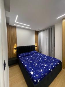 a bedroom with a bed with a blue blanket at Klindi Apartaments in Pogradec