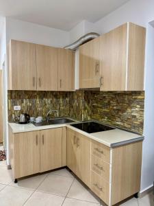 a kitchen with wooden cabinets and a sink at Apartament Niko Shengjin 1 in Shëngjin +2 photos