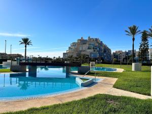 a swimming pool in a park with palm trees and a building at Playa Serena 2 habitaciones PRIMERA LINEA DE PLAYA Vista al Mar in Roquetas de Mar