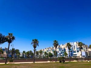 a large building with palm trees in front of it at Playa Serena 2 habitaciones PRIMERA LINEA DE PLAYA Vista al Mar in Roquetas de Mar