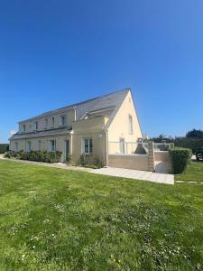 a large white house with a green lawn at Gîtes de la Mouette L'Estran 8 à 9 personnes in Ravenoville